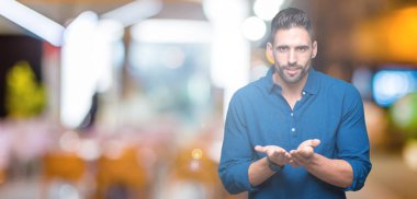 Yakışıklı delikanlı izole arka plan üzerinde gülen ellerle birlikte alma veya jest vererek palms. Ayrı tutma ve koruma