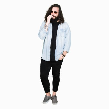 Uzun saç ve sakal stresli ve gergin ile güneş gözlüğü takmış genç hipster adamla tırnak ısırma dudaklarından eller. Anksiyete sorunu.