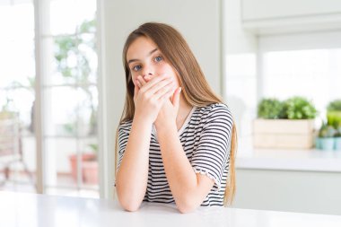 Çizgili tişört giyen güzel genç kız çocuk hata için elleri ile ağız kapsayan şok. Gizli kavram.