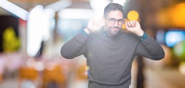 Üzerinde gözlük takan genç yakışıklı adam arka plan gülen çekerek kulakları parmaklar, komik jest ile izole. Seçmelere sorun