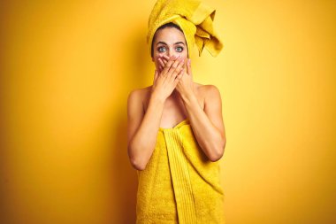 Güzel kadın vücut ve baş üzerinde duş havlusu giyen sarı izole arka plan üzerinde hata için elleri ile ağız kapsayan şok. Gizli kavram.
