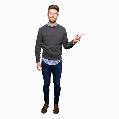 Yüzünde kocaman bir gülümseme ile genç yakışıklı zarif adam kameraya bakarak yan el ve parmak ile işaret.