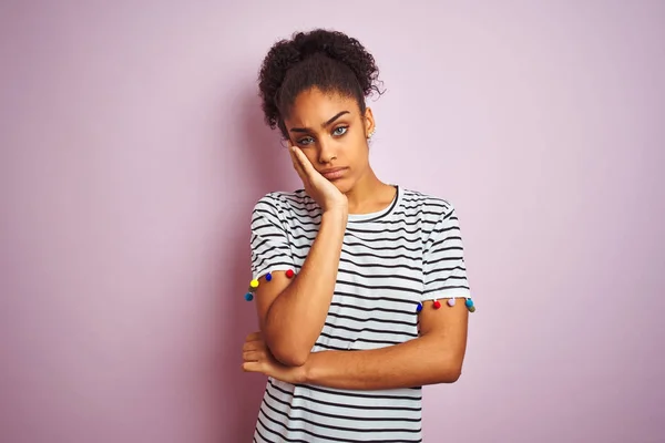 African american woman wearing navy striped t-shirt standing over isolated pink background thinking looking tired and bored with depression problems with crossed arms.