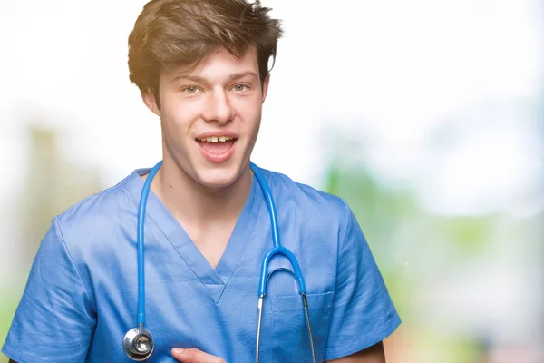 年轻的医生穿着医疗制服在孤立的背景微笑和笑得很大声 因为有趣的疯狂笑话 愉快的表达 — 图库照片