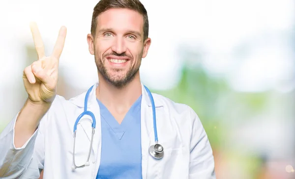 上医療制服を着てハンサムな医者男分離を示す背景と自信を持って 幸せな笑みを浮かべている間 つ番号を指で上向き — ストック写真