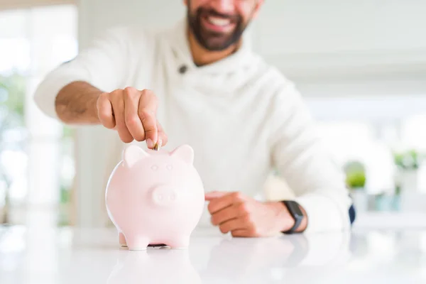 Homem sorrindo colocando uma moeda dentro do banco porquinho economizando para inves — Fotografia de Stock