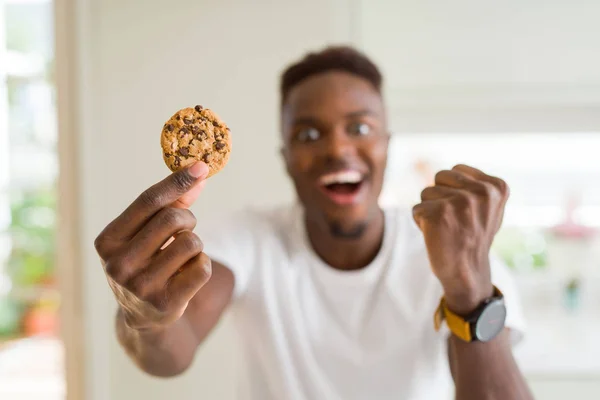 Joven Afroamericano Hombre Comiendo Galletas Chips Chocolate Gritando Orgulloso Celebrando — Foto de Stock