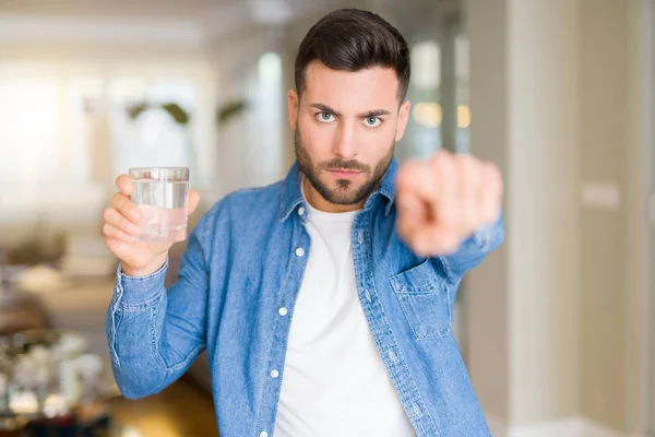 Joven Hombre Guapo Bebiendo Vaso Agua Casa Señalando Con Dedo —  Fotos de Stock