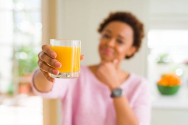 Genç Afrikalı Amerikan kadın ev ciddi yüz soru hakkında düşünme, çok karışık fikir portakal suyu elsanatı