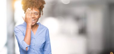 Güzel genç Afro-Amerikan iş kadını el yüz ve sürpriz duygu kendinden emin gülümseme ile tek gözüyle kapsayan izole arka plan üzerinde.
