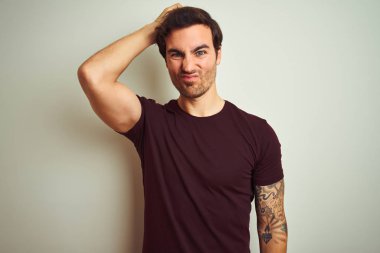 Izole beyaz arka plan üzerinde mor rahat t-shirt giyen dövme ile genç yakışıklı adam karıştırmayın ve soru hakkında merak ediyorum. Şüpheyle belirsiz, eliyle kafada düşünmek. Pensive kavramı.