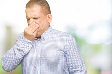 Bir şey pis ve iğrenç kokulu izole arka plan, dayanılmaz koku, holding nefes burun parmak ile orta yaş Arap iş adamı. Kötü kokuyor kavramı.