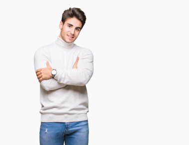 İzole arka plan üzerinde balıkçı yaka kazak giyen genç yakışıklı adam fotoğraf makinesi bakarak çapraz silah ile gülümseyen yüz. Pozitif kişi.