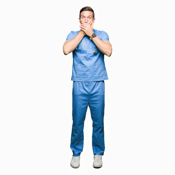 Muž Pohledný Doktor Lékařských Uniformě Izolované Pozadí Šokován Pokrývající Ústa — Stock fotografie