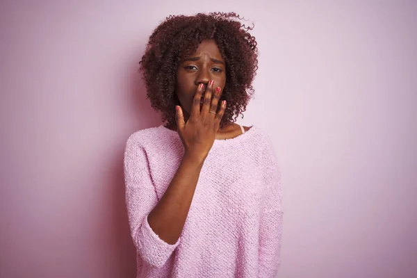Young african afro woman wearing sweater standing over isolated pink background bored yawning tired covering mouth with hand. Restless and sleepiness.