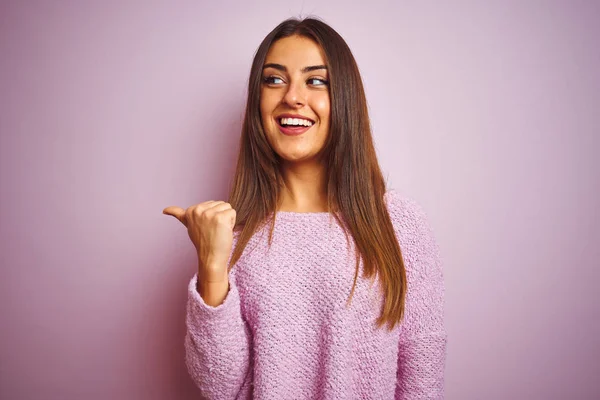 年轻的美丽的女人穿着休闲毛衣站在孤立的粉红色背景微笑与快乐的脸看 并指着一边竖起大拇指 — 图库照片