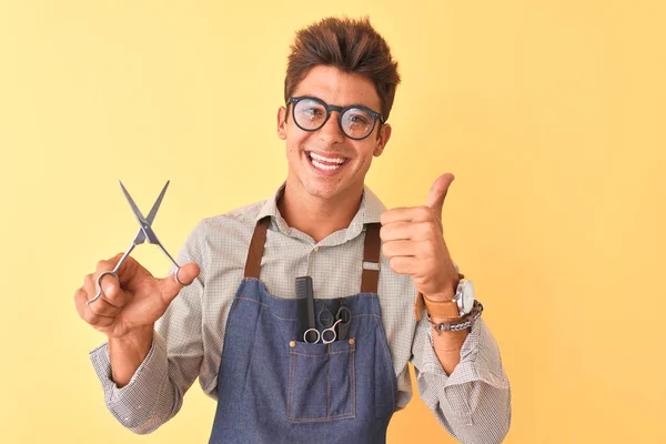 Hombre Guapo Peluquero Con Delantal Sosteniendo Tijeras Sobre Fondo Amarillo — Foto de Stock