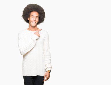 Afro saçlı genç afro-amerikan adam kış kazak neşeli bir yüz yüzü ile işaret eden bir gülümseme ile yan yana mutlu ve doğal ifade ile