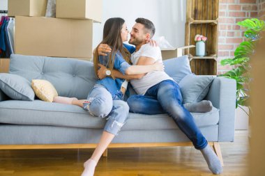 Kanepede aşık güzel çift sarılmak, çok mutlu yeni ev için heyecanlı gülümseyen