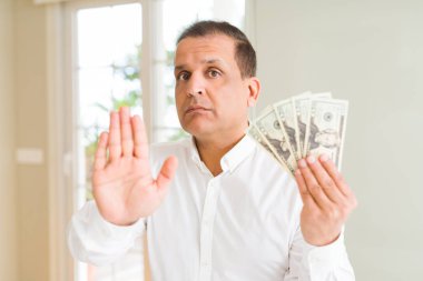 Orta yaş erkek holding grup dolar açık eliyle dur işareti ile ciddi ve kendine güvenen ifade, savunma hareketi yapıyor