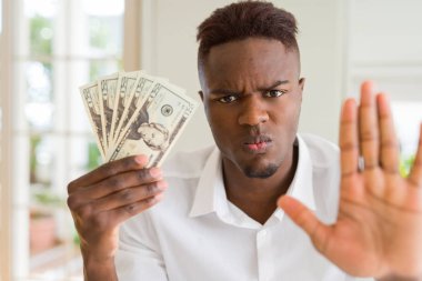 Afro-amerikan adam açık el ciddi ve kendinden emin ifade, savunma jesti ile dur işareti yapıyor yirmi dolar banka notları tutan