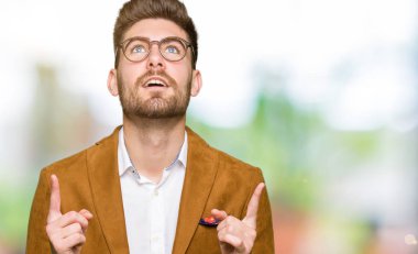 Gözlüklü genç yakışıklı iş adamı şaşırtmak ve yukarıya bakıp parmakları ile işaret şaşırttı ve silah kaldırdı.