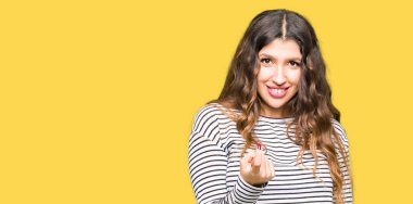 Beckoning gel burada mutlu ve gülümseyerek el davet ile jest kazak giyen genç güzel kadın çizgili