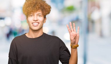Gösterilen ve parmakları ile işaret siyah t-shirt giyen afro saçlı Genç yakışıklı adam kendinden emin ve mutlu gülümseyerek süre dört numara.