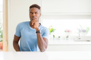 Yakışıklı afro-amerikan adam evde rahat t-shirt giyen çene üzerinde el ile soru, dalgın ifade düşünme. Düşünceli bir yüzle gülümsüyor. Şüphe kavramı.
