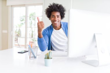 Afrikalı-Amerikalı adam çalışma mutlu ok işareti yapıyor büyük gülümseme ile bilgisayarla başparmak yukarı parmaklarıyla, mükemmel işareti