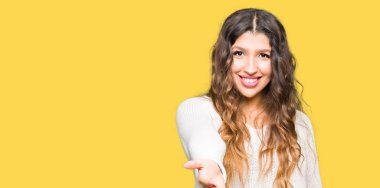 Tebrik ve konuksever dost sunan karşılıklı gülümseyen beyaz kazak giyen genç güzel kadın. Başarılı iş.