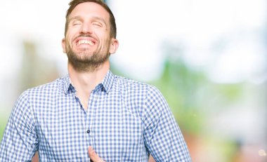 Mavi gözleri ile yakışıklı iş adamı gülümsüyor ve sert yüksek sesle gülüyor Çünkü komik çılgın şaka. Mutlu ifade.