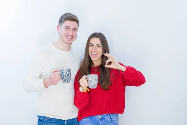 美丽的年轻夫妇在白色孤立的背景喝一杯咖啡做好标志用手指 优秀的符号 — 图库照片
