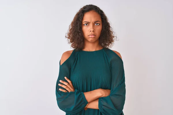 Young brazilian woman wearing green t-shirt standing over isolated white background skeptic and nervous, disapproving expression on face with crossed arms. Negative person.