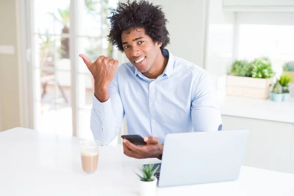 スマートフォンとラップトップを使ったアフリカ系アメリカ人ビジネスマンが 笑顔で親指を立てて顔を出す — ストック写真