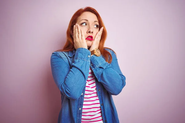 Beautiful redhead woman wearing denim shirt and striped t-shirt over isolated pink background Tired hands covering face, depression and sadness, upset and irritated for problem