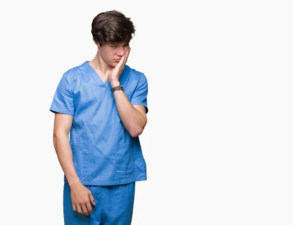 疲れていて 組んだ腕のうつ病問題にうんざりして孤立した背景を考えての上医療ユニフォーム身に着けている若い医者 — ストック写真