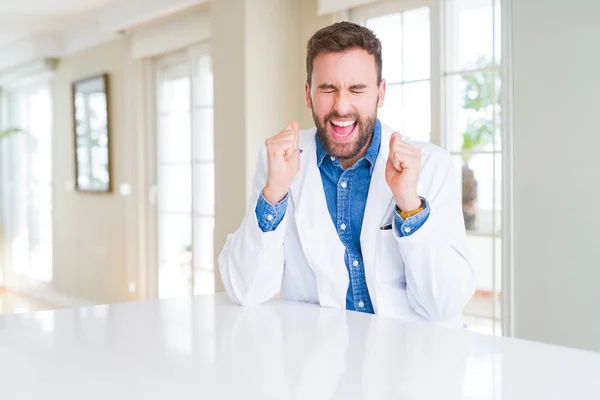 クリニックで医療コートを着たハンサムな医者の男は 勝利を祝う笑顔を上げた腕で成功に興奮しました 勝者のコンセプト — ストック写真