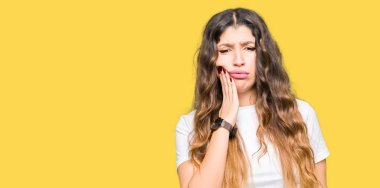 Genç güzel kadın diş ağrısı veya diş üzerinde diş hastalığı nedeniyle ağrılı ifade ile el ile ağız dokunmadan rahat beyaz t-shirt giyiyor. Diş hekimi konsepti.