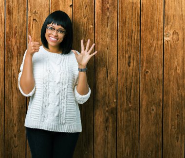 Güzel genç Afro-Amerikan kadın gözlük gösterilen ve parmakları ile işaret izole arka plan üzerinde kendinden emin ve mutlu gülümseyerek süre 6 numara.