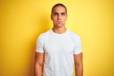 Genç beyaz adam komik yüzü ile yanakları şişirme sarı izole arka plan üzerinde rahat beyaz t-shirt giyiyor. Ağız hava ile şişirilmiş, deli ifade.