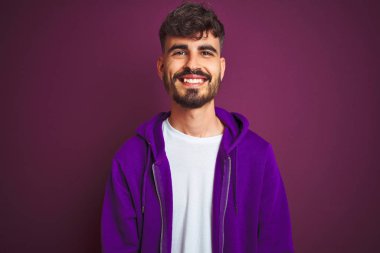 Dövme li genç adam yüzünde mutlu ve serin bir gülümseme ile izole sarı arka plan üzerinde duran çizgili polo giyiyor. Şanslı kişi.