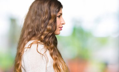 Tarafa bakarak beyaz kazak giyen genç güzel kadın dinlenmek doğal yüz emin gülümseme ile pozuyla profili.