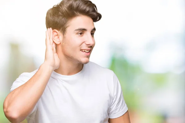 若いハンサムな男の噂やゴシップに審理をリスニングの耳に手を浮かべて分離の背景に白い シャツを着てします 難聴の概念 — ストック写真