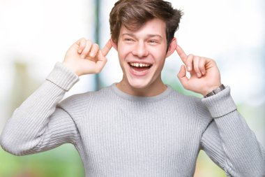 Üzerinde kış kazak giyen genç yakışıklı adam arka plan gülen çekerek kulakları parmaklar, komik jest ile izole. Seçmelere sorun