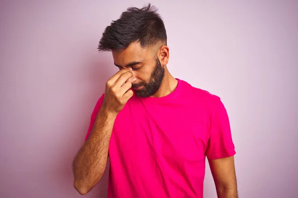 분홍색 배경에 티셔츠를 남자는 피로와 두통을 느끼는 문지르는 스트레스와 — 스톡 사진