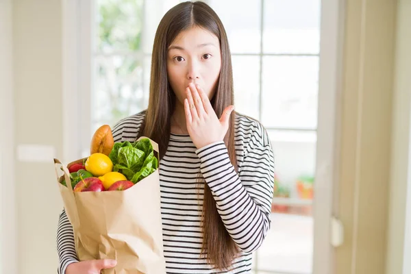 新鮮な食料品の紙袋を持つ美しいアジアの女性は 間違いの恥ずかしさ 恐怖の表現 沈黙の中で怖がって 秘密の概念でショックを受けた手で口を覆う — ストック写真