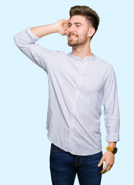 Genç, yakışıklı, kendine güvenen, el hareketleriyle saçlara dokunan çekici bir adam.