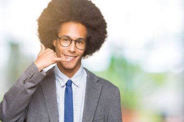 Afro saçlı gözlüklü yapıyor gülümseyen genç Afro-Amerikalı iş adamı telefon hareketi ile el ve parmak telefonda konuşuyor gibi. Kavramları iletişim.