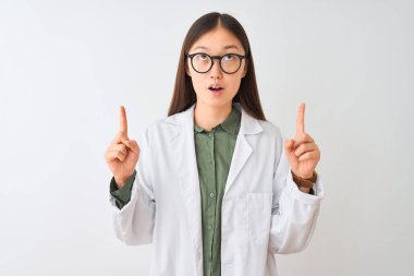 İzole beyaz arka plan üzerinde palto ve gözlük takan genç Çinli bilim adamı kadın şaşırttı ve baktı ve parmakları ile işaret ve kolkaldırdı şaşırttı.